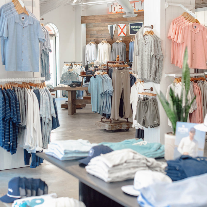 Interior of Toes on the Nose Huntington Beach store featuring premium boardshorts on display, vintage lockers, and a rustic wooden wall with branded signage