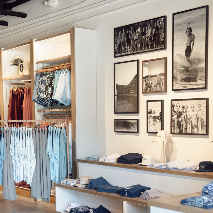 Curated clothing wall featuring polos, sweatshirts, and hats at Toes on the Nose San Juan Capistrano store