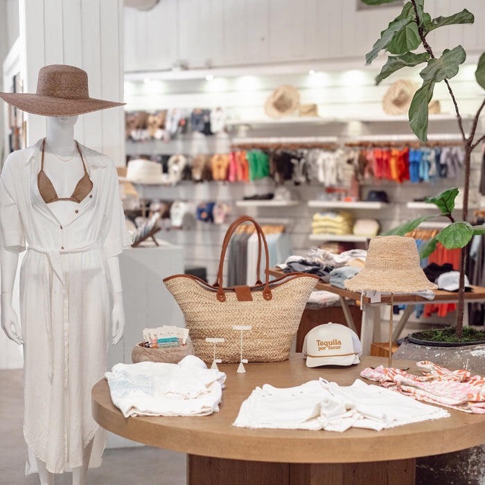Interior view of the Toes on the Nose clothing store in Huntington Beach, showcasing a wide selection of premium surf apparel on mannequins and displays, including sweaters, shirts, shorts, and accessories, reflecting a casual coastal lifestyle