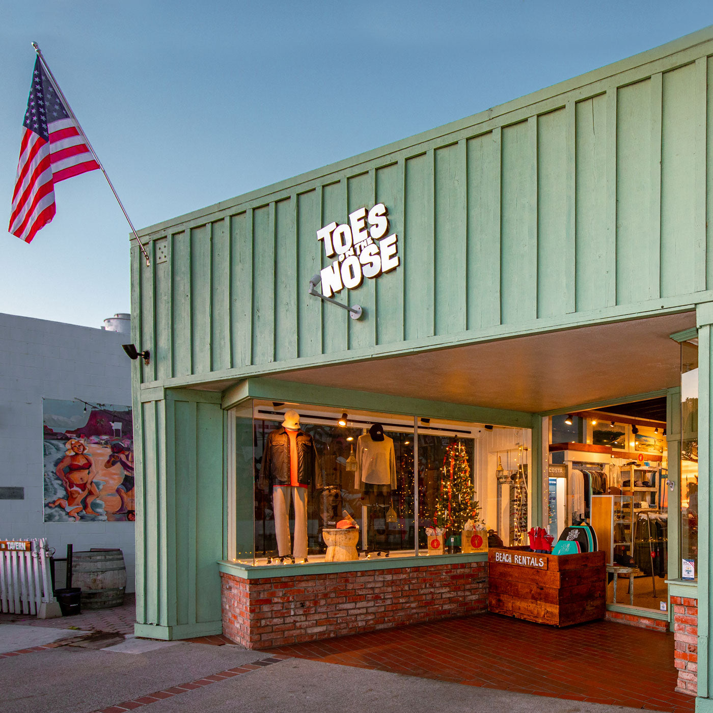 Exterior of Toes on the Nose surf shop in Laguna Beach with American flag and ocean-inspired storefront