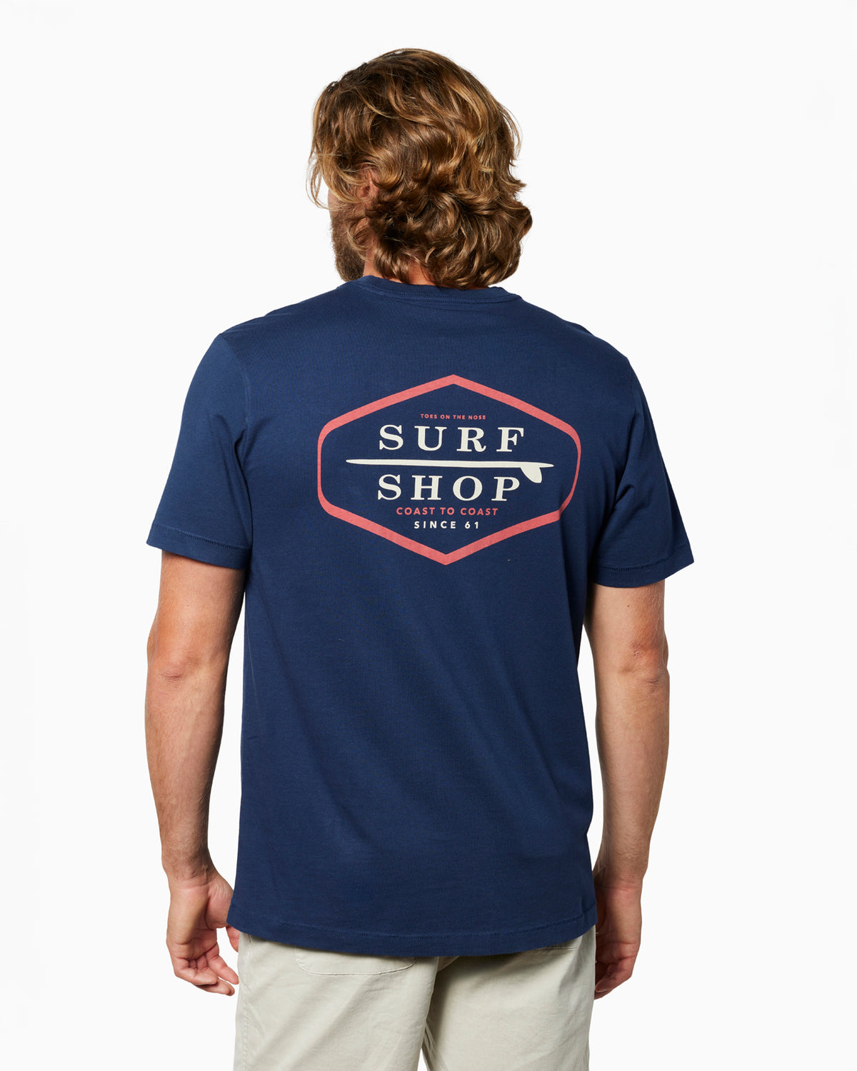 Man wearing a navy blue t-shirt with 'Surf Shop' logo on the back, standing against a white background. #color_navy