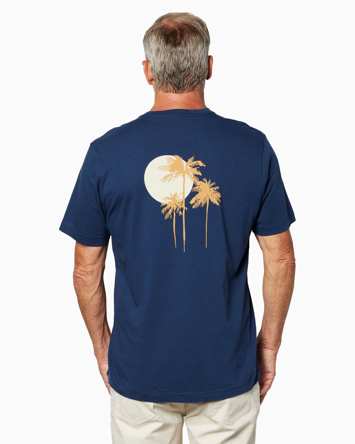 Man in a navy t-shirt with palm tree design on the back, standing against a white background. #color_navy