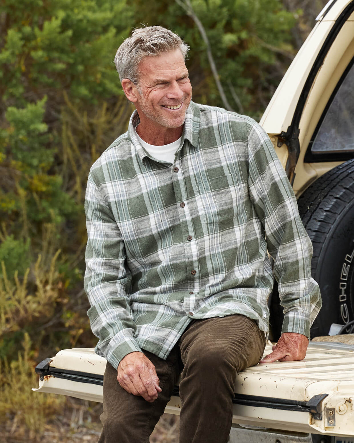 Men's olive flannel from Toes on the Nose, worn in a lifestyle setting outdoors. #color_olive plaid