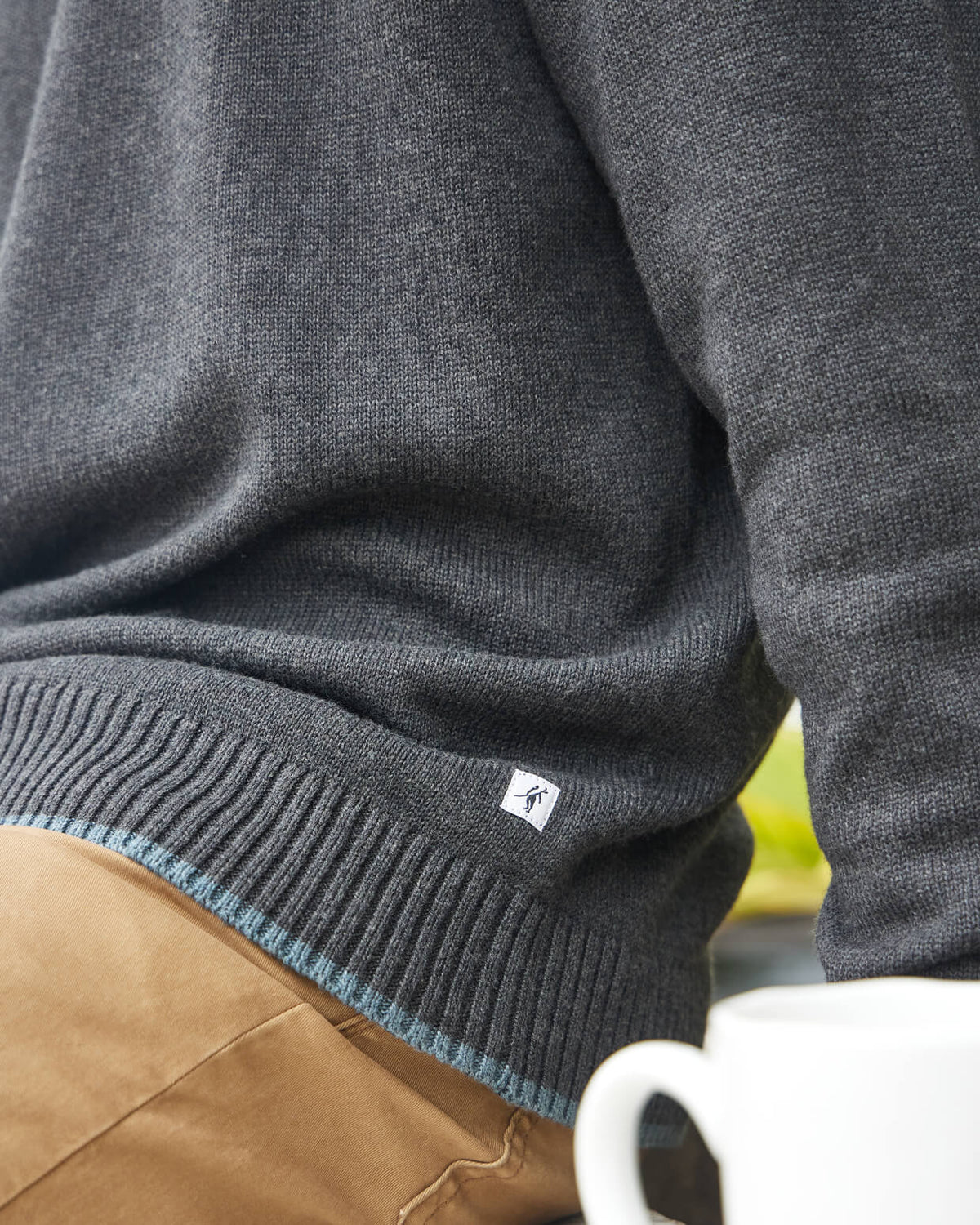 Heather smoke sweater with Toes on the Nose worn by a person, sitting on a ledge #color_heather smoke