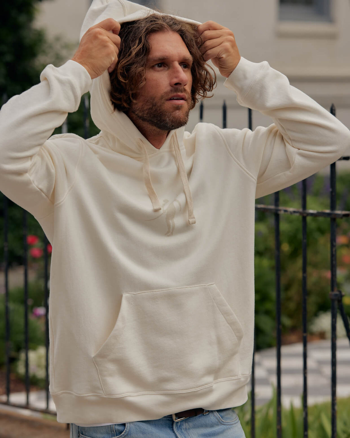 Men's vintage white logoi hoodie from Toes on the Nose, worn in a lifestyle setting outdoors. #color_vintage white