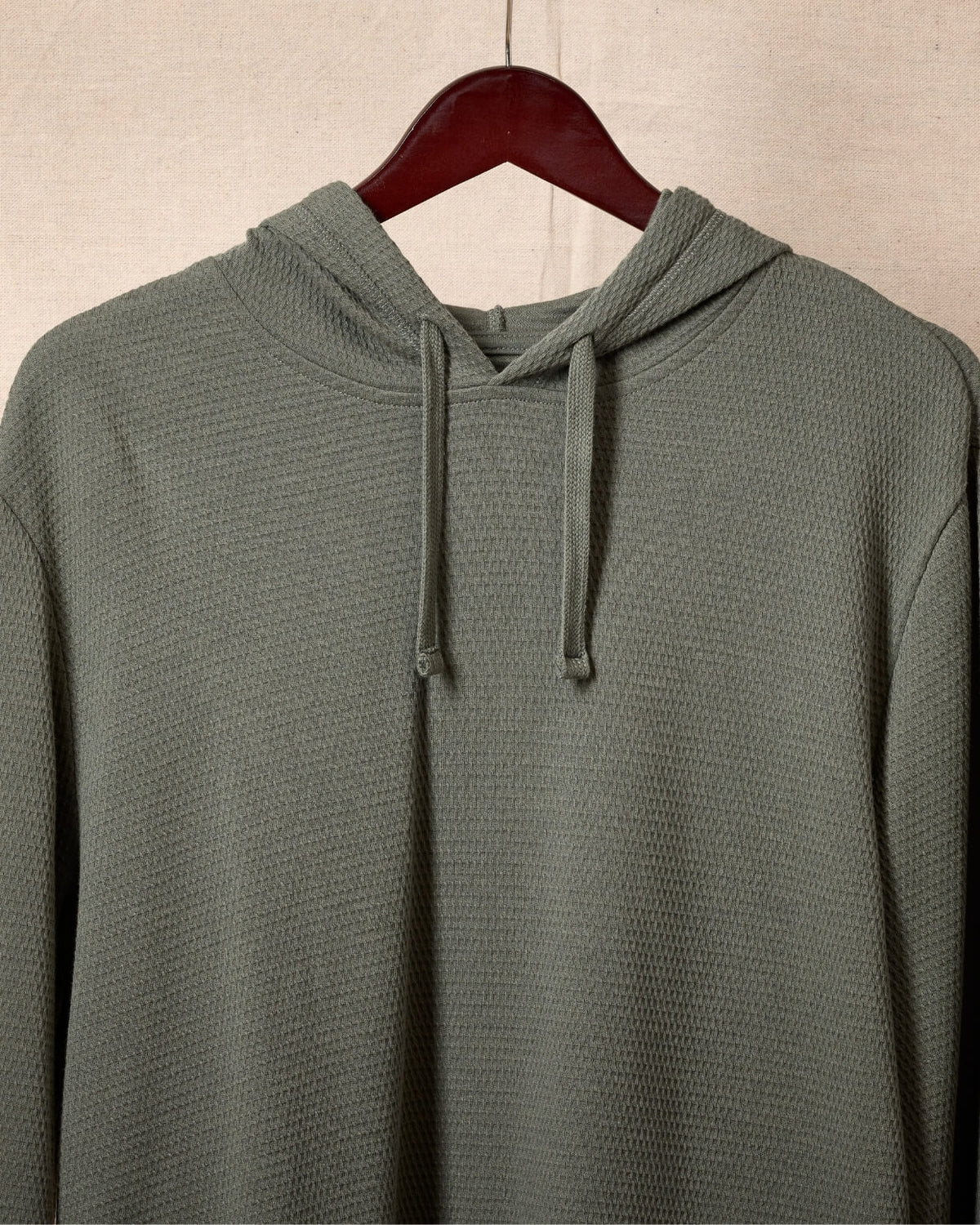 A dark green textured pullover hoodie with matching black drawstrings, displayed flat against a canvas background. #color_deep sage