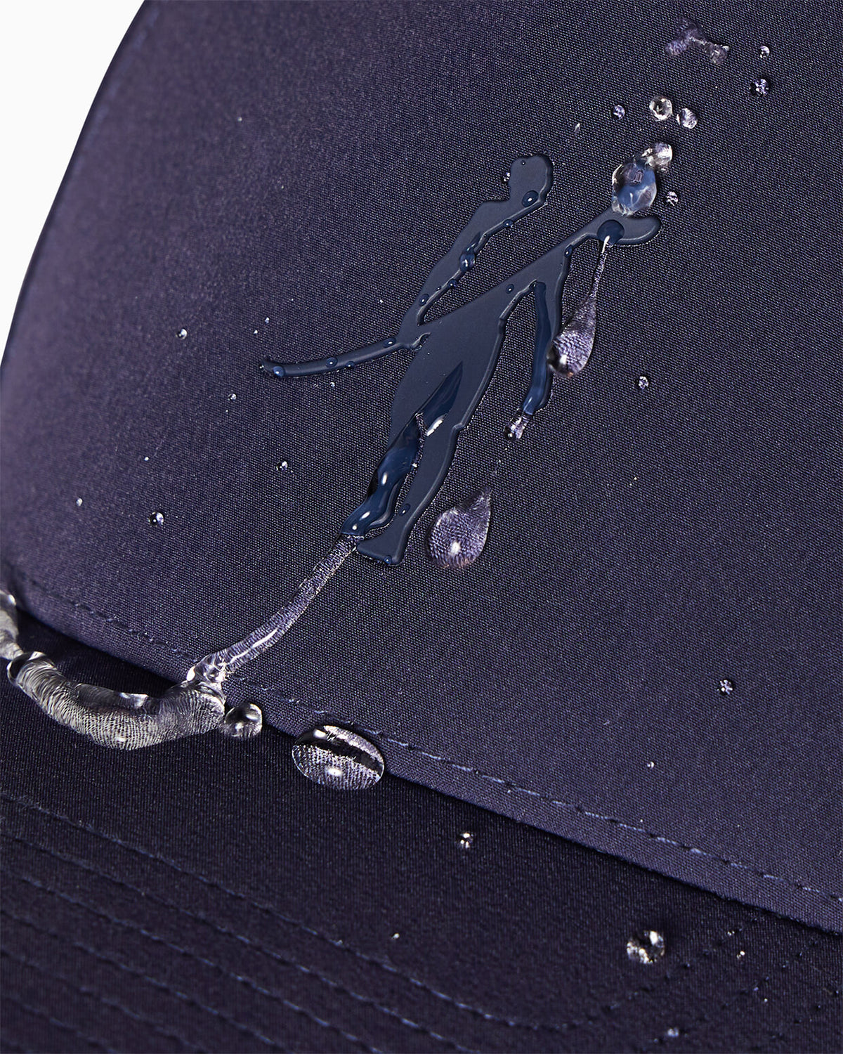 Close-up of navy performance baseball cap with Toes on the Nose logo and water-beading hydrophobic finish, detail view.