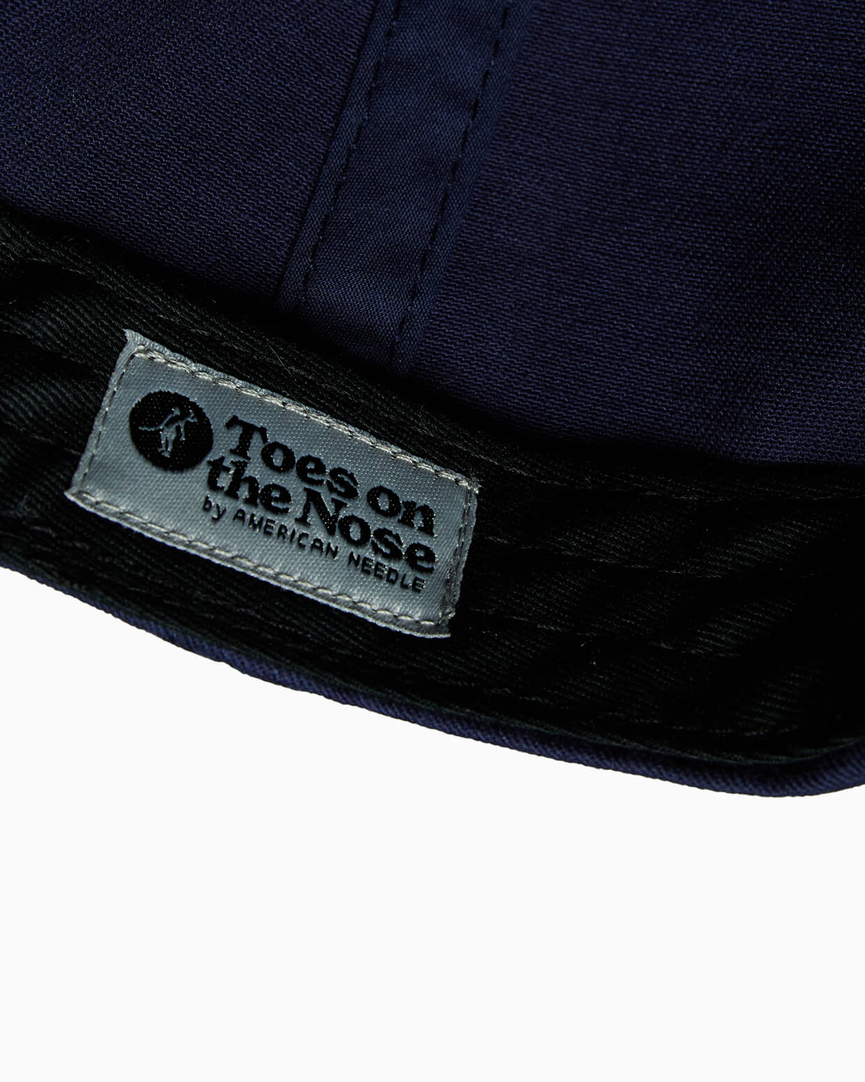 "Toes on the Nose brand tag sewn into the inside of a navy blue baseball cap."