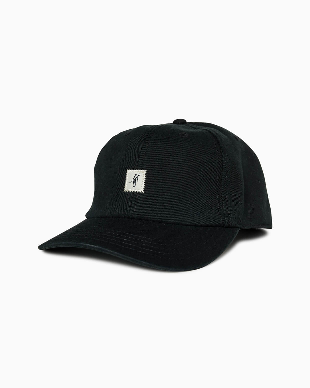 Black baseball cap with small square Toes on the Nose surfer patch, angled studio view.