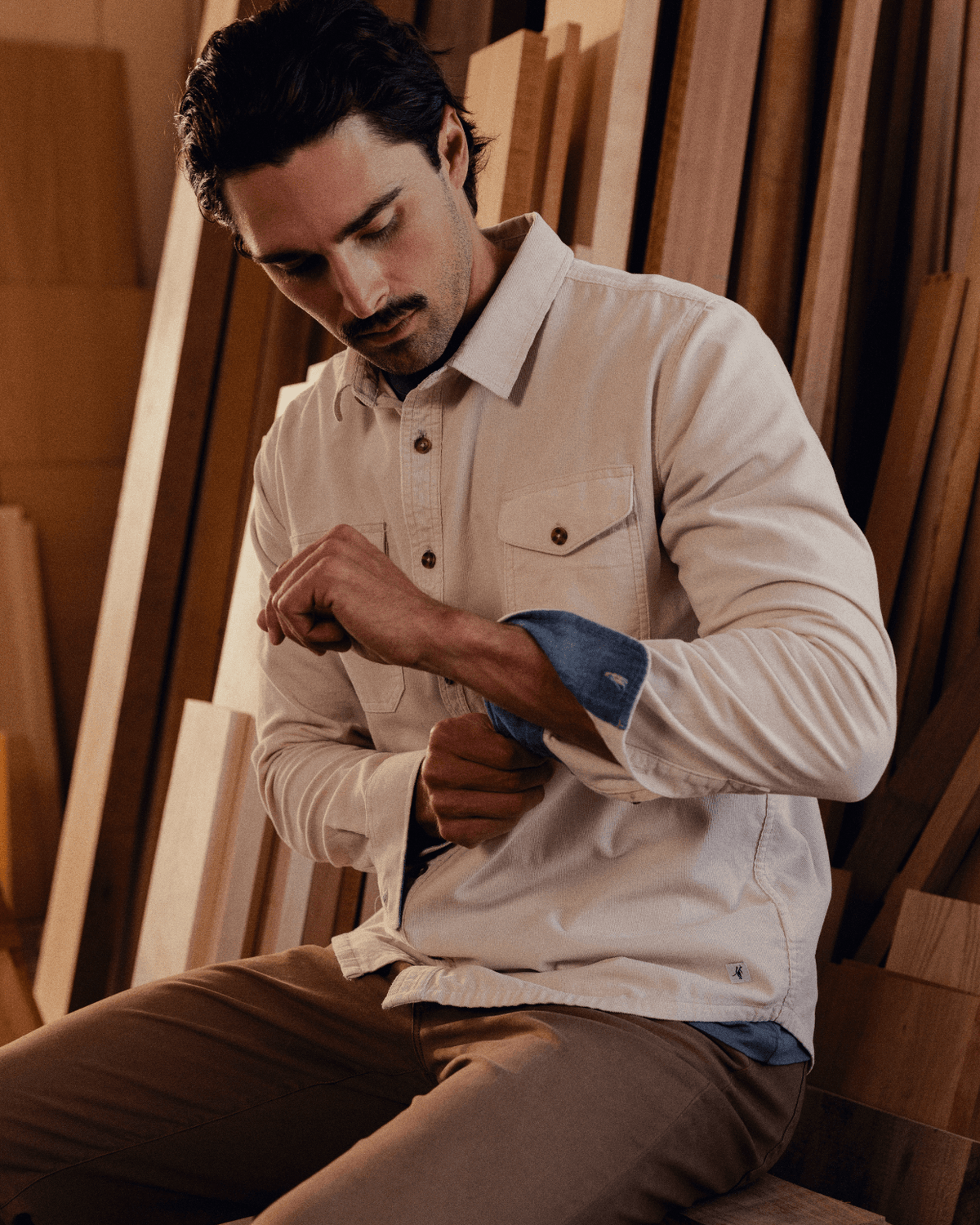 Man adjusting his shirt sleeve in a wooden workshop #color_merit birch