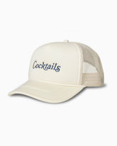 Cream mesh-back trucker hat with navy “Cocktails” embroidery, angled studio view.