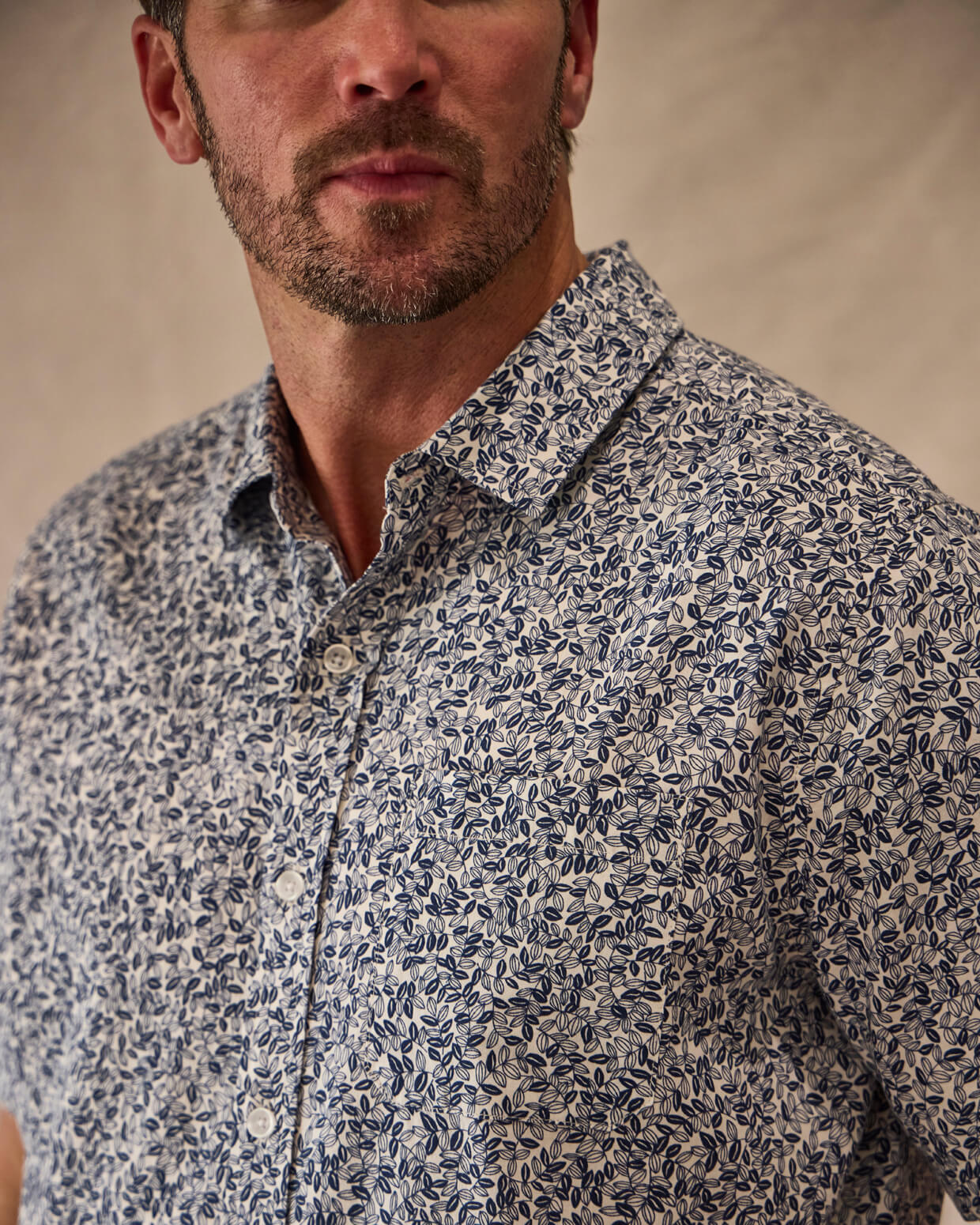 Man wearing a patterned shirt against a beige background